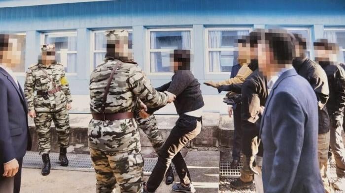 Guards drag a man at the border between North and South Korea