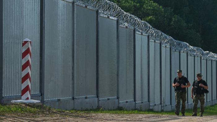 Polish border guards patrol along a fence