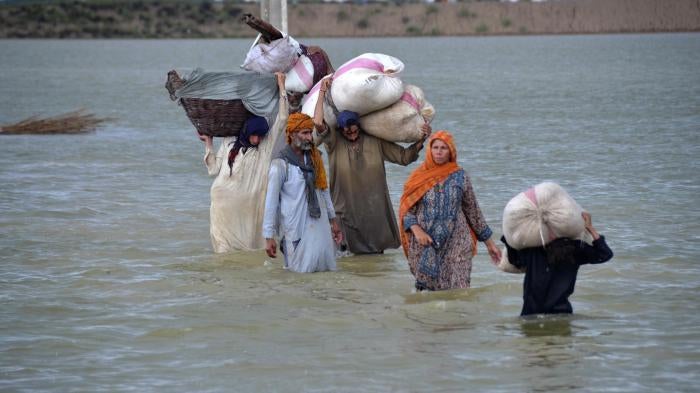 A displaced family wades through a flooded area in Jaffarabad