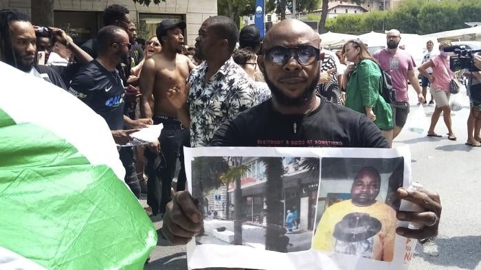 A man shows a picture of the victim Nigerian street vendor Alika Ogorchukwu