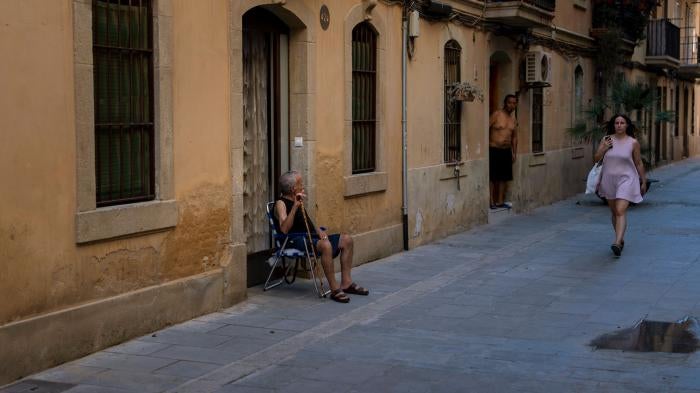 An older man sits outside his house during a heat wave in Barcelona, Spain