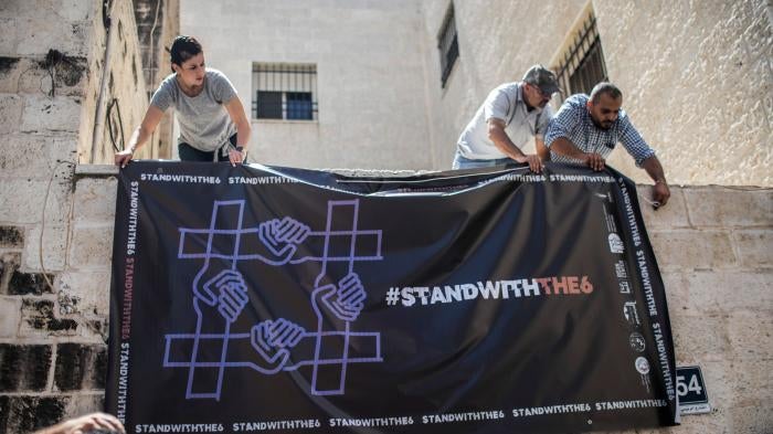 Activists hang a poster outside a Palestinian civil society organization