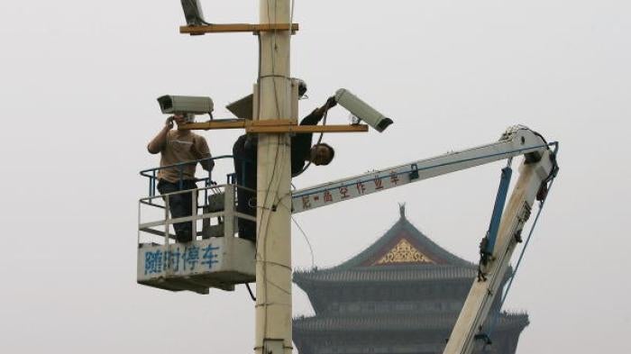 Labourers adjust newly installed surveillance cameras at Tiananmen Square ahead of National Day on September 28, 2005.
