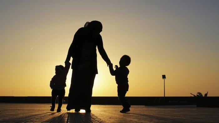 A woman walks with her two children at sunset near the seashore in Benghazi.