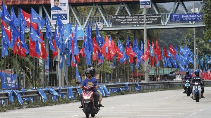 Motorcyclists ride past political party flags in Kuala Lumpur.