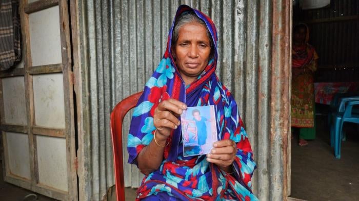 An older woman holds up a photo of a child