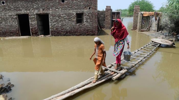 A woman and girl walk on a temporary bamboo path near their flooded house in Shikarpur, Pakistan.