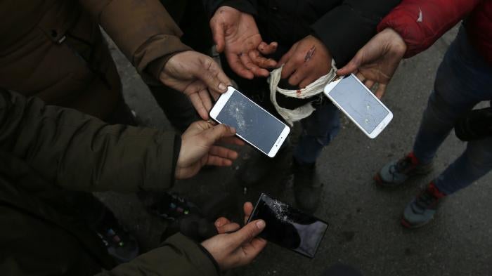 Migrants show broken phones in the village of Horgos, Serbia