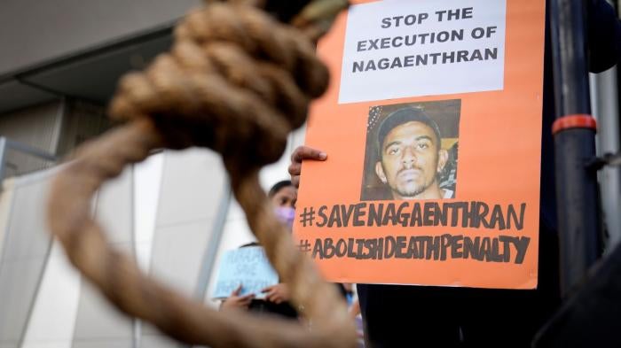 An activist holds a poster opposing the impending execution of Nagaenthran Dharmalingam