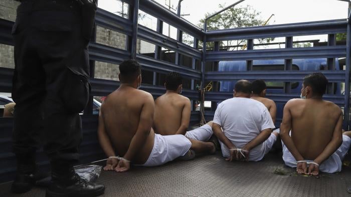 People arrested by police wait in zip tie handcuffs in the back of a truck to be transferred to a prison at the Police Delegation of San Bartolo in Soyapango, El Salvador, Tuesday, Aug. 16, 2022.