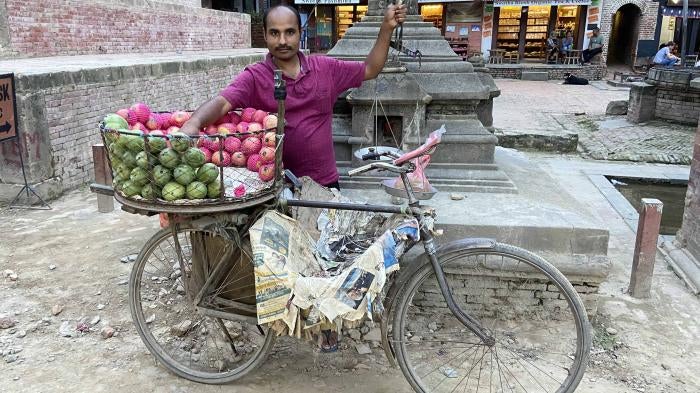A man poses for a photo with his fruit cart