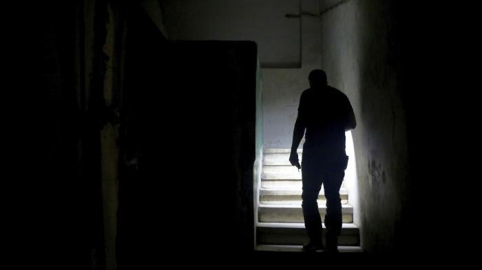 رجل في بيروت يستخدم مصباح هاتفه الخلوي ليصعد الدرج حتى يصل إلى شقته أثناء انقطاع التيار الكهربائي في يوليو/تموز 2020. 