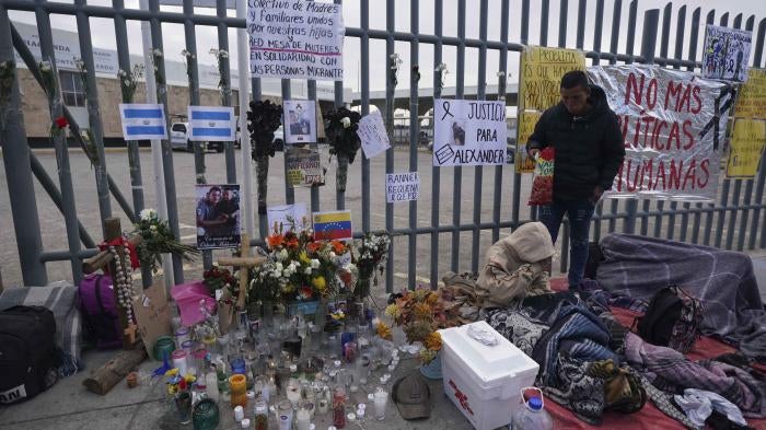 An altar with candles and photos covers the fence outside a Mexican immigration detention center