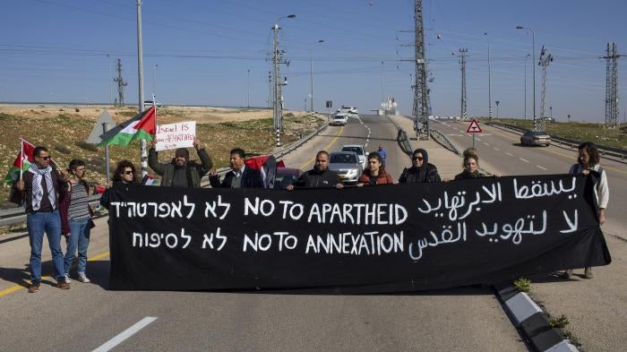  Israeli and Palestine activists hold a banner during a protest to block the new Route 4370 Israeli highway near the Palestinian town of Anata, January 23, 2019.