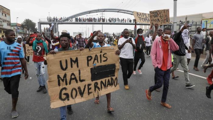 People hold up a sign that reads “A country badly governed” during a march against rising fuel prices and the end of street vending in Luanda, Angola, June 17, 2023. © 2023 ROGERIO/EPA-EFE/Shutterstock