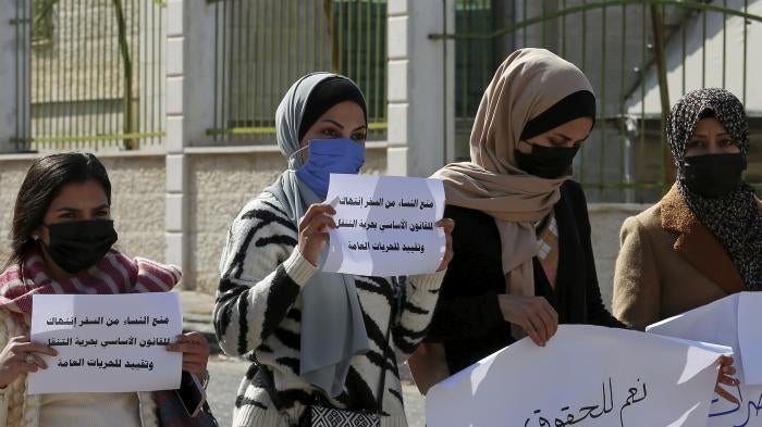 Women hold signs in Arabic during a protest 