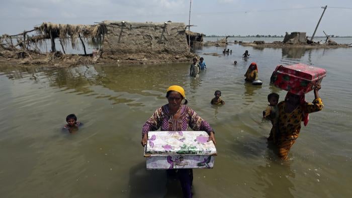 Women carry belongings salvaged from their flooded homes after monsoon rains in the Qambar Shahdadkot district of Sindh province, Pakistan, September 6, 2022.