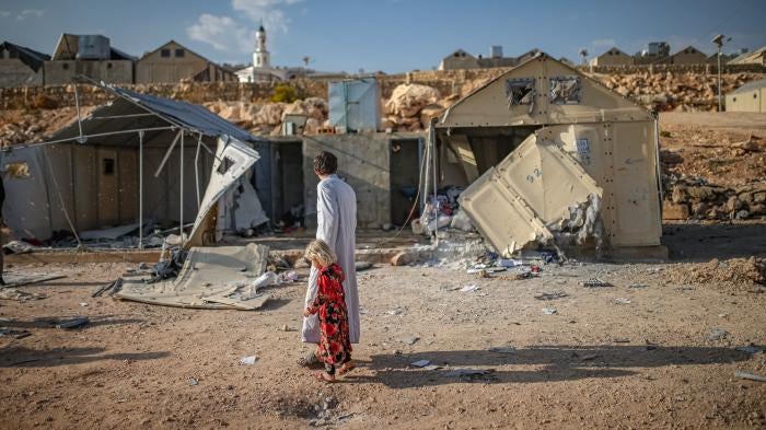 أشخاص يقيمون الأضرار الناجمة عن الهجوم بالذخائر العنقودية الذي شنه التحالف العسكري السوري الروسي على مخيم مرام للنازحين بالقرب من قرية كفر جالس في محافظة إدلب، شمال غرب سوريا، في 6 تشرين الثاني/نوفمبر 2022.