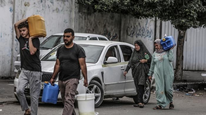 Palestinians carry their bottles of water after Israeli authorities have ceased supplying electricity, water and food in the Gaza Strip, October 17, 2023.