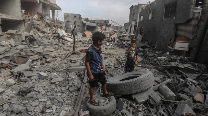 Palestinian children stand amid the rubble of destroyed buildings in Al-Bureij camp, Gaza