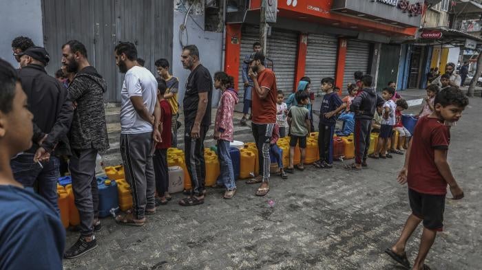 Palestinians stand in line to get water in the city of Rafah in the southern Gaza Strip amid ongoing hostilities between Israeli forces and Palestinian armed groups, November 13, 2023. 