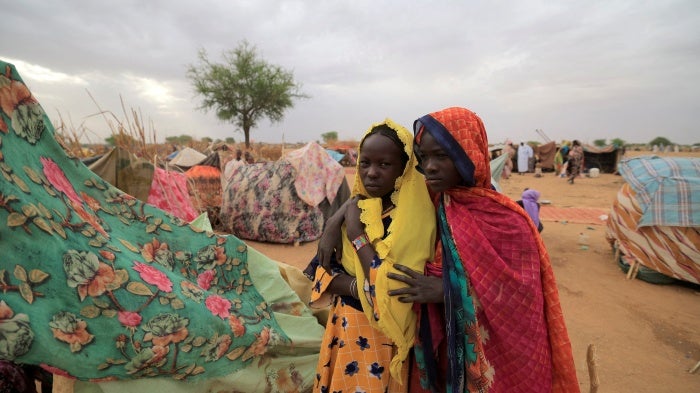 Nadia, a Sudanese refugee who has fled the violence in Sudan's Darfur region, hugs her friend Khadidja, beside makeshift shelters near the border between Sudan and Chad in Koufroun, Chad on May 11, 2023. 