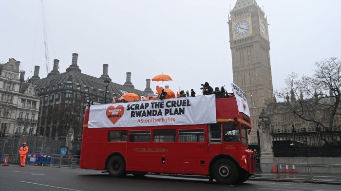 Protesters hold a banner on a red double decker bus 