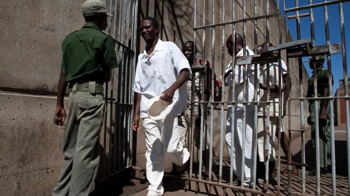 Inmates walk past a prison guard at the Chikurubi maximum security prison in Harare, Zimbabwe, May 20, 2015.