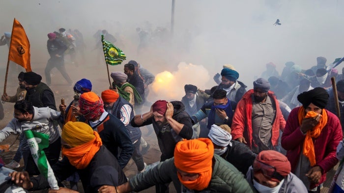 Protesting farmers flee exploding tear gas shells.
