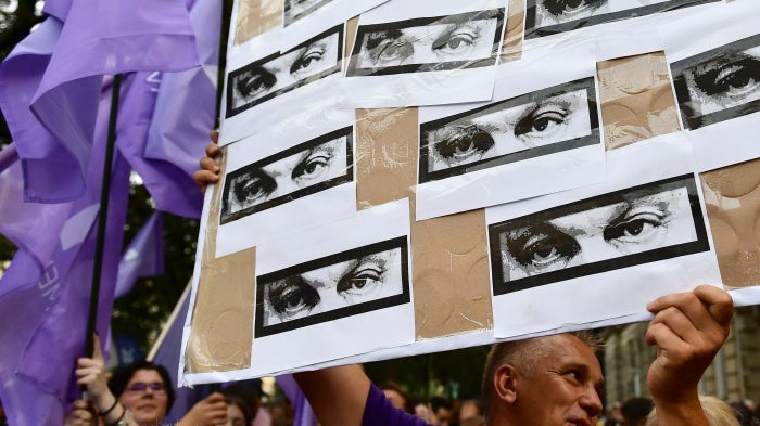 A man holds a banner showing the eyes of Hungarian Prime Minister Viktor Orban during a protest