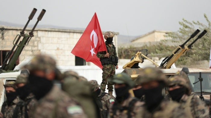 An unidentifiable soldier holds a Turkish flag