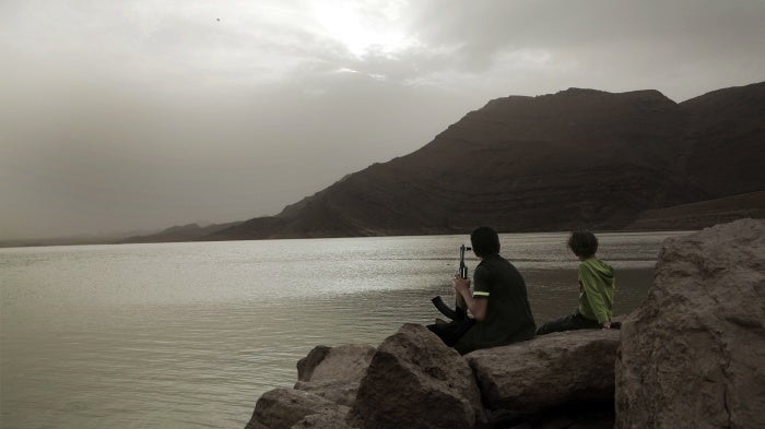 A boy, believed to be recruited by the Houthis, holds an AK-47 while overlooking the high dam in Marib, Yemen, July 30, 2018.