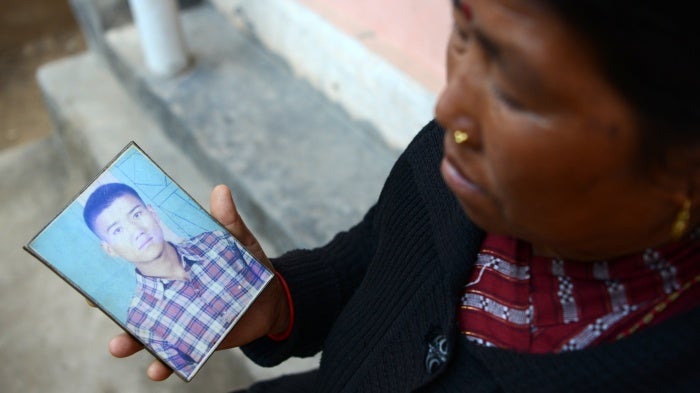 A woman displays a photograph of her son