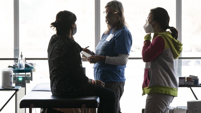 Volunteers offer free physical therapy services for a patient at the Seattle/King County Clinic, during an annual free healthcare event held at Seattle Center on February 16, 2024.