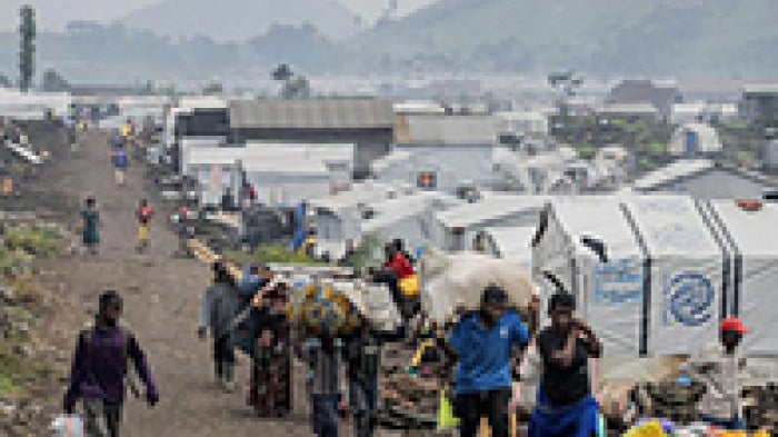 Group walks through camp of tents.