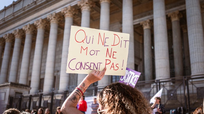 An individual holding a sign saying “Not saying anything does not equal consent”  in front of the Palais de Justice during a rally in support of all victims of gender and sexual violence in Lyon, France, October 19, 2024.