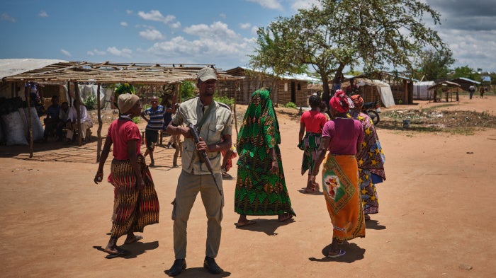 A police officer patrols in front of women in a shelter for internally displaced people