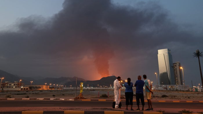 Foreign workers watch a plume of black smoke following an explosion in the Fujairah industrial zone in the United Arab Emirates, March 3, 2026. 