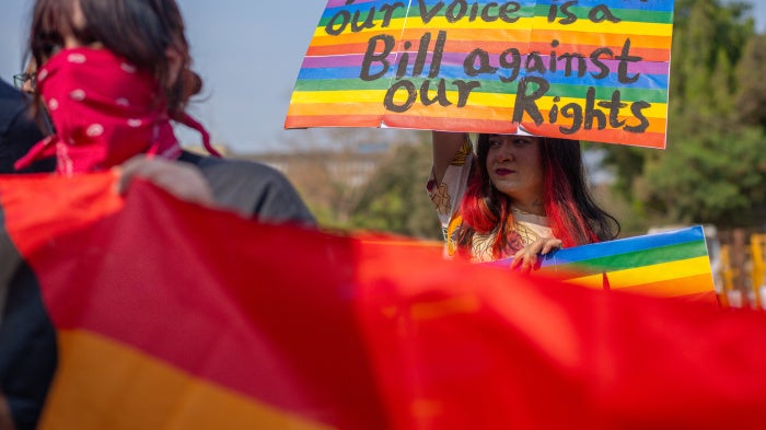 An activist holds a placard at a protest that reads "A bill without our voice is a bill against our rights"