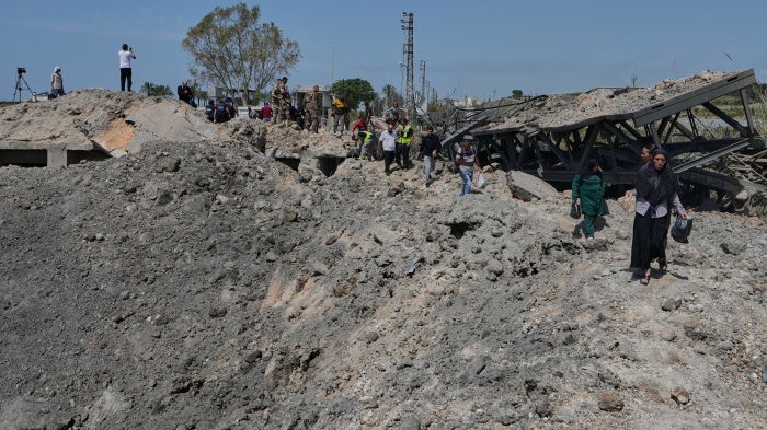People cross on foot through a crater following an Israeli airstrike that destroyed the Qasmieh Bridge near the coastal city of Tyre, south Lebanon, April 16, 2026.
