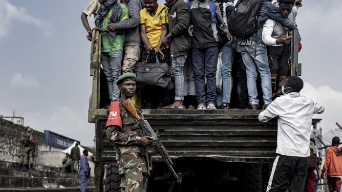 M23 fighters stand guard as people board a truck