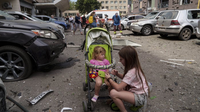Children wait near the site of Okhmatdyt children’s hospital hit by Russian missiles, in Kyiv, Ukraine, Monday, July 8, 2024.