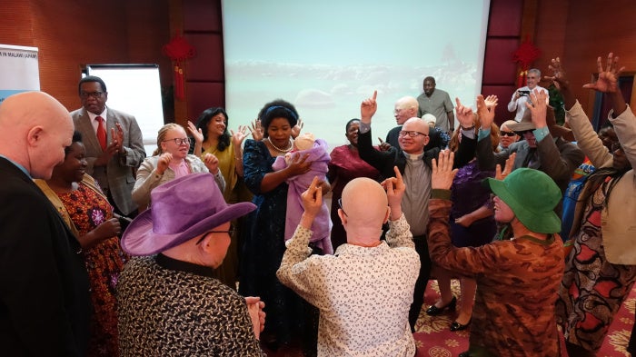 During the June 12 launch of the joint report by Human Rights Watch and African Albinism Network on discrimination against people with albinism in employment, Malawi’s Minister of Gender, Children, Disability and Social Welfare dances with a young child with albinism as community members gather around them on the eve of International Albinism Awareness Day in Lilongwe. 