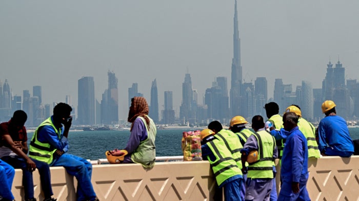Workers sit on a wall against the backdrop of the city skyline, Dubai, UAE, March 11, 2026.