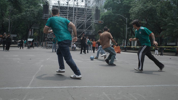 Passersby take part in a pickup football game organized by civilian search collectives on Mexico City's Paseo de la Reforma during the World Cup, July 2026. 