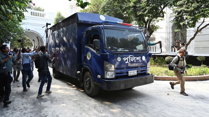 Journalists swarm a blue prison van