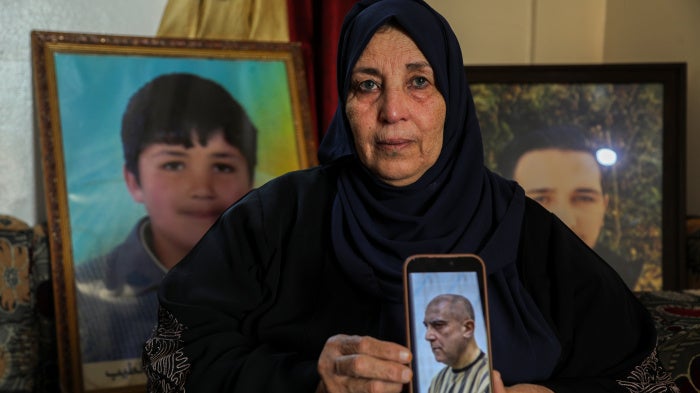 Samira Hahami stands in front of photos of her son, Hamza Ali al-Khatib, who at the age of 13 in May 2011, died in security forces custody. His body bore apparent signs of torture.