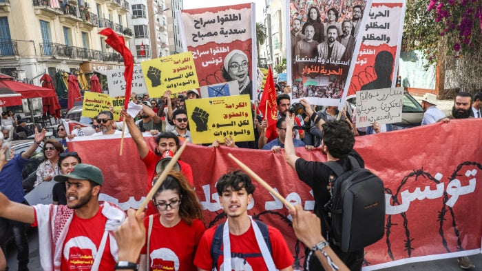Tunisians hold up placards during a march organized by the Campaign Against the Criminalization of Civil Work to protest racism in Tunis, April 11, 2026