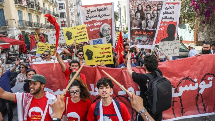 Tunisians hold up placards during a march organized by the Campaign Against the Criminalization of Civil Work to protest racism in Tunis, April 11, 2026