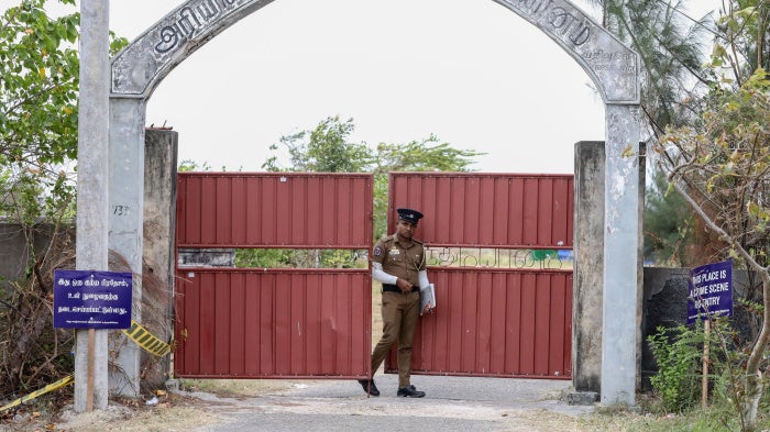 A police officer stands guard in front of the Chemmani mass grave site in Jaffna, Sri Lanka, July 26, 2025.